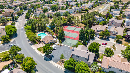 Aerial images over a community in Antioch, California with houses, cars, streets and trees. With a blue sky and room for text