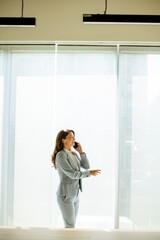 Young woman using mobile phone by the office window