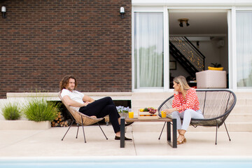 Young couple relaxing by the swimming pool in the house backyard