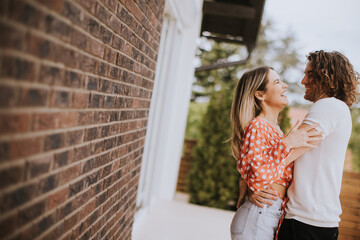 Smiling young couple in love in front of house brick wall