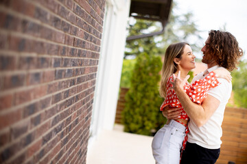 Smiling young couple in love in front of house brick wall