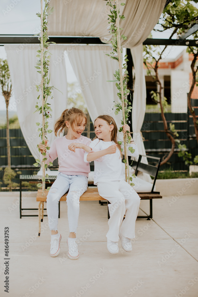 Wall mural Cute little girls on the swing in the house backyard