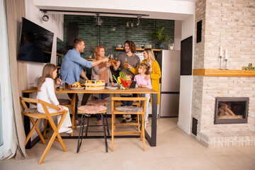 Two families toasting with cider while preparing dinner in the kitchen