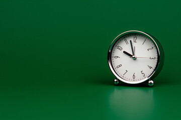 Fototapeta na wymiar alarm clock silver white dial on green screen Working with time. Be on time. Keep time. Value time concept.