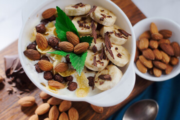 Fruit salad with peeled almonds, banana and mint in a white plate. Advertising photo. View from above.