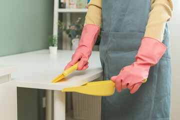 Household hygiene clean up, housekeeper woman hand in pink rubber protective gloves with yellow broom and dustpan sweeping remove dust on table at home, equipment or tool for cleaning, cleaner people.