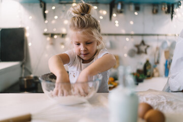 Little girl preparing dough at home