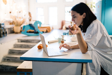 Young woman using laptop while cooking