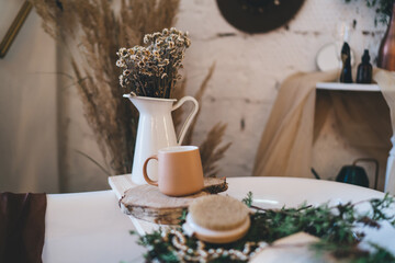 Ceramic jug with flowers and coffee cup on sink in kitchen
