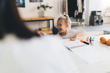 Cute little girl sitting at table with marker pens