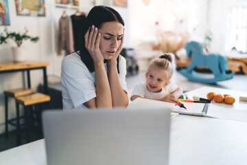 Tired woman sitting at table with child