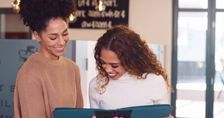 Two friendly female coworkers discuss report standing in office, laughing