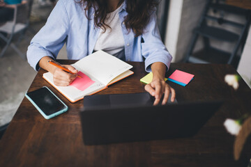Obraz premium Woman with laptop taking notes in planner