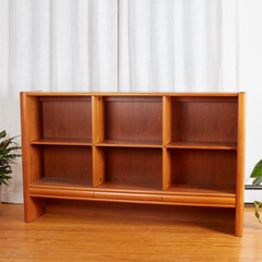 Vintage teak display case bookshelf. Mid-century modern design furniture. Interior view before luxurious white curtains and lively houseplants.