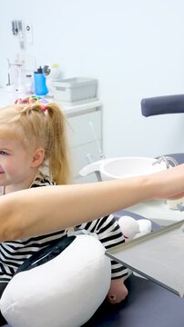 young doctor showing little girl dental chair first trip to dentist happy happiness smile pleasant conversation milk teeth treatment nurse fair-haired girl child 
