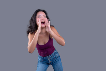 girl in a shouting gesture with hands near her mouth. isolated on a gray background.