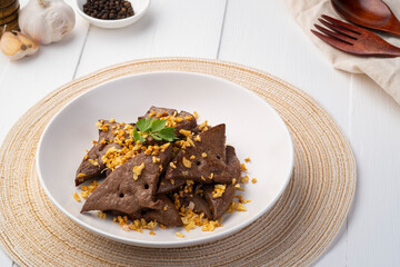Fried Pork Liver with Garlic,Stir fry sliced liver with black peppercorn and garlic in white plate.