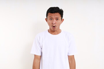 Shocked asian funny man standing while looking at camera. Isolated on white