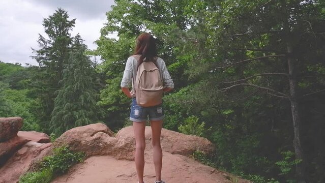 Woman traveler on the top of the mountain looks at the beautiful landscape. Girl tourist enjoys vacation, travel, adventure, nature. High quality FullHD footage
