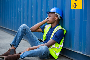 African American worker and resting sit at container box at construction site. Contractor or...