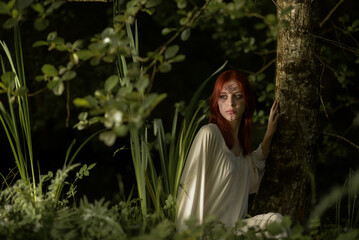 beautiful girl with red hair on the bank of the pond
