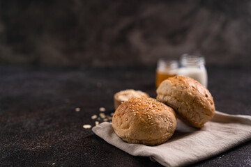 Fresh whole grain brown buns with sesame seeds on rustic background. Healthy artisan bread.