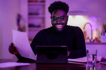 A happy interracial virtual assistant is sitting at home at night and having a video call with a client.