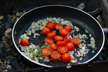 roasted cherry tomato with garlic and onion in pan on barbecue coal