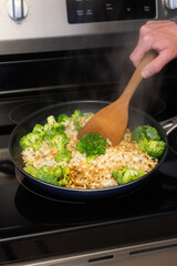 Cooking broccoli and noodles stir fry in a pan 