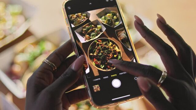 Woman taking street food photos on mobile phone, screen close-up