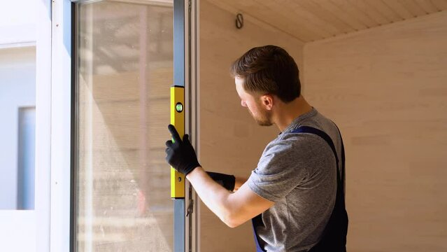 Worker measures of the vertical deviation of pvc windows in wooden modular house