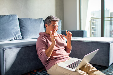 Middle aged hispanic man using a laptop at home