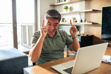Naklejka premium Middle aged man working on his laptop and going over his bills at home
