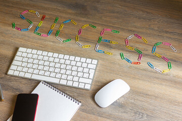The word success collected from colored paper clips on a wooden table.