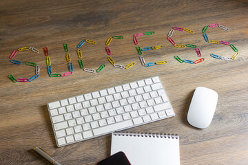 The word success collected from colored paper clips on a wooden table.