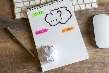 The concept of the idea is sketched in a notebook. The keyboard and mouse are on a wooden table.