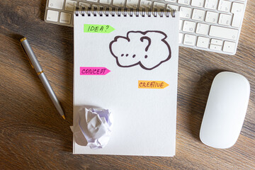 The concept of the idea is sketched in a notebook. The keyboard and mouse are on a wooden table.