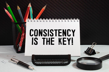 Notebook with text CONSISTENCY IS THE KEY on wooden table