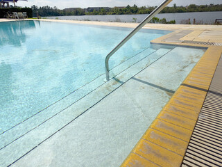 A view of an infinity style swimming pool overlooking a lake, in a Southern Florida landscape.