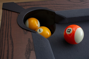 A view of a some pool balls next to a corner pocket.