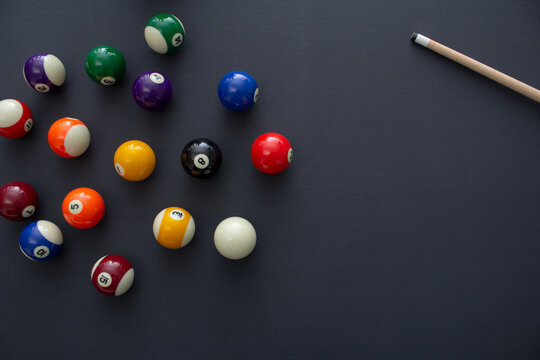 A top down view of a pool balls and a cue stick on a blue felt table.