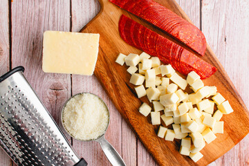 Prepped Pepperoni, Mozzarella, and Parmesan Cheese on a Wooden Background: Sliced pepperoni with...