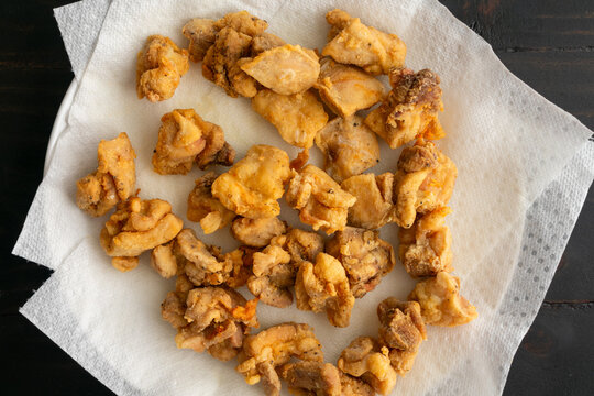 Close-Up Of Fried Pieces Of Chicken Draining On Paper Towels: Deep-fried Bite-size Chicken Thigh Nuggets On A Paper Towel-covered Plate