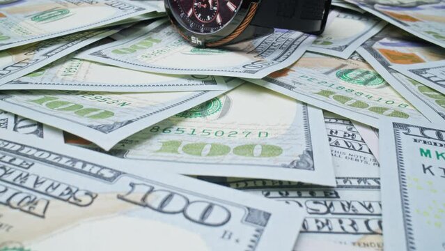 Concept of finance and money payment. Extreme close-up one hundred dollar bills with wrist watch. Time is money. Dolly shot. Fiat money. Camera moving. 4K, UHD