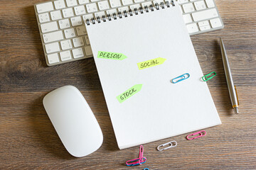 On a wooden table is a keyboard and mouse, a pen with a notepad with stickers with inscriptions on it.