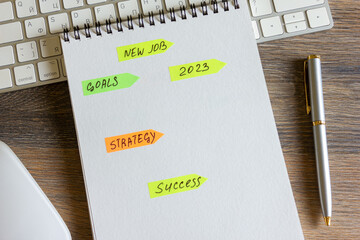 On a wooden table is a keyboard and mouse, a pen with a notepad with stickers with inscriptions on it.