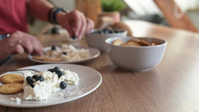 Cottage chease at plate with blueberries and cookies for healthy breakfast at home. Milk cream desert for organic meal nutrition with berries and sweet galletas