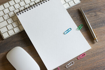 Keyboard with mouse, notepad and pen on a wooden table.