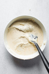 milk being folded into cake batter, Lemon cake batter in a white mixing bowl, cake batter being folded with a spatula, the process of making lemon pound cake