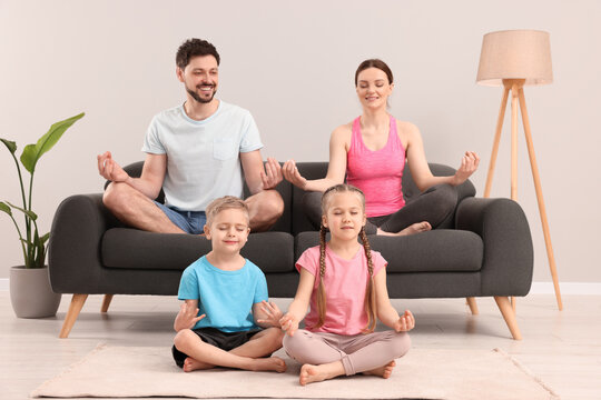 Happy family meditating together at home. Harmony and zen